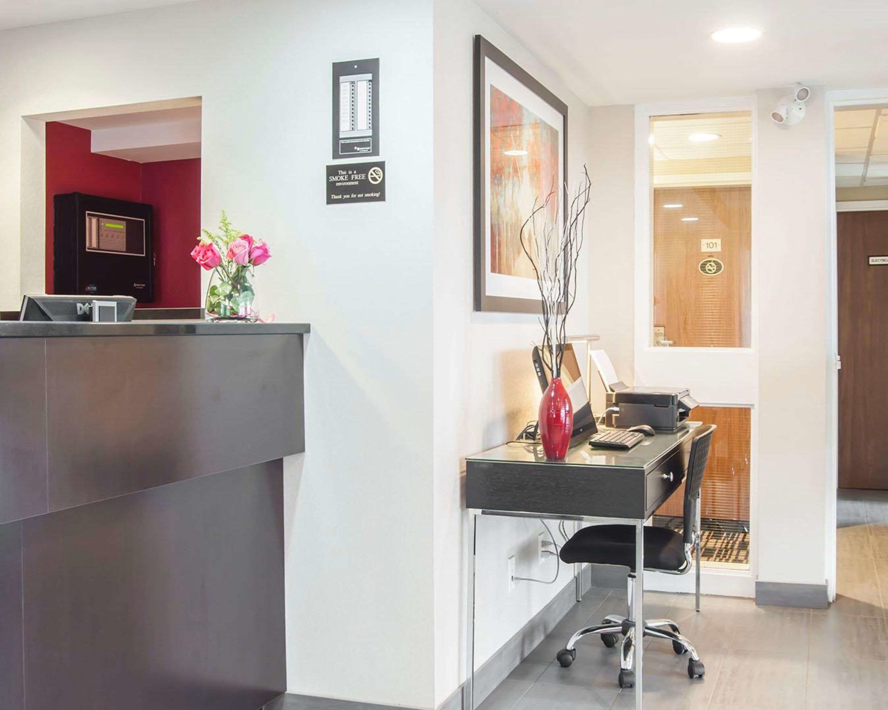 A reception area with a desk, a phone, a vase with flowers, and a framed picture on the wall.