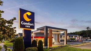 A Comfort Inn hotel with a modern design, featuring a prominent sign and a well-maintained outdoor area with neatly trimmed bushes. - Comfort Inn (Fredericton)