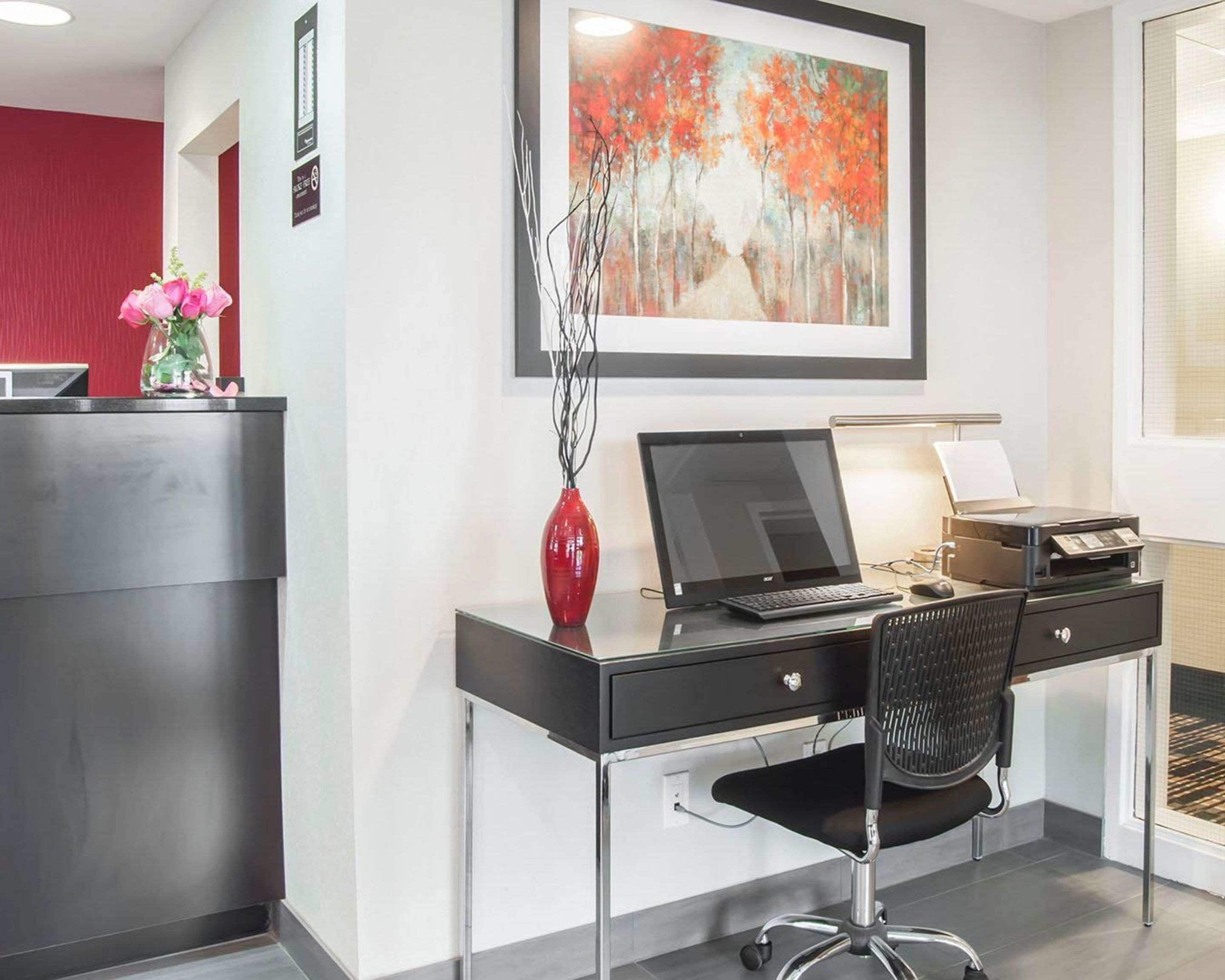 Un bureau moderne, équipé d’un ordinateur portable, d’une imprimante et d’un vase décoré de branches.