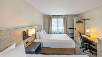 Hotellihuone, jossa on kaksi sänkyä, työpöytä, tuoli ja vaatekaappi.