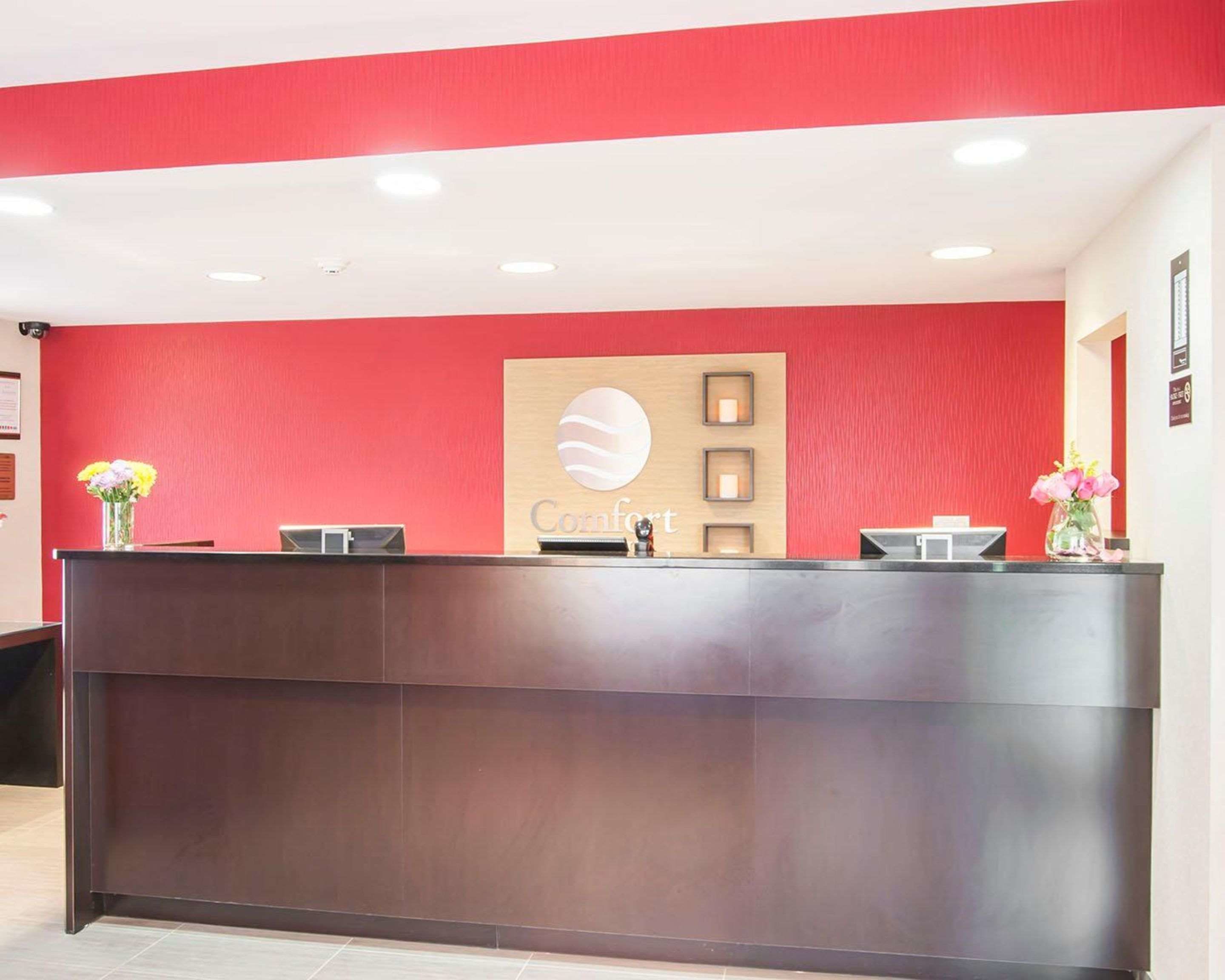 Ein Empfangsschalter mit roter Wand und einem Logo mit der Aufschrift 'Comfort'.