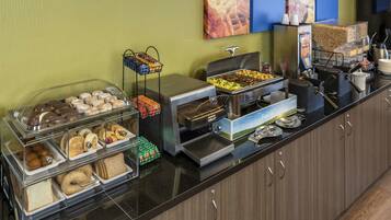 A buffet with various food items, including pastries, sandwiches, and a coffee station.