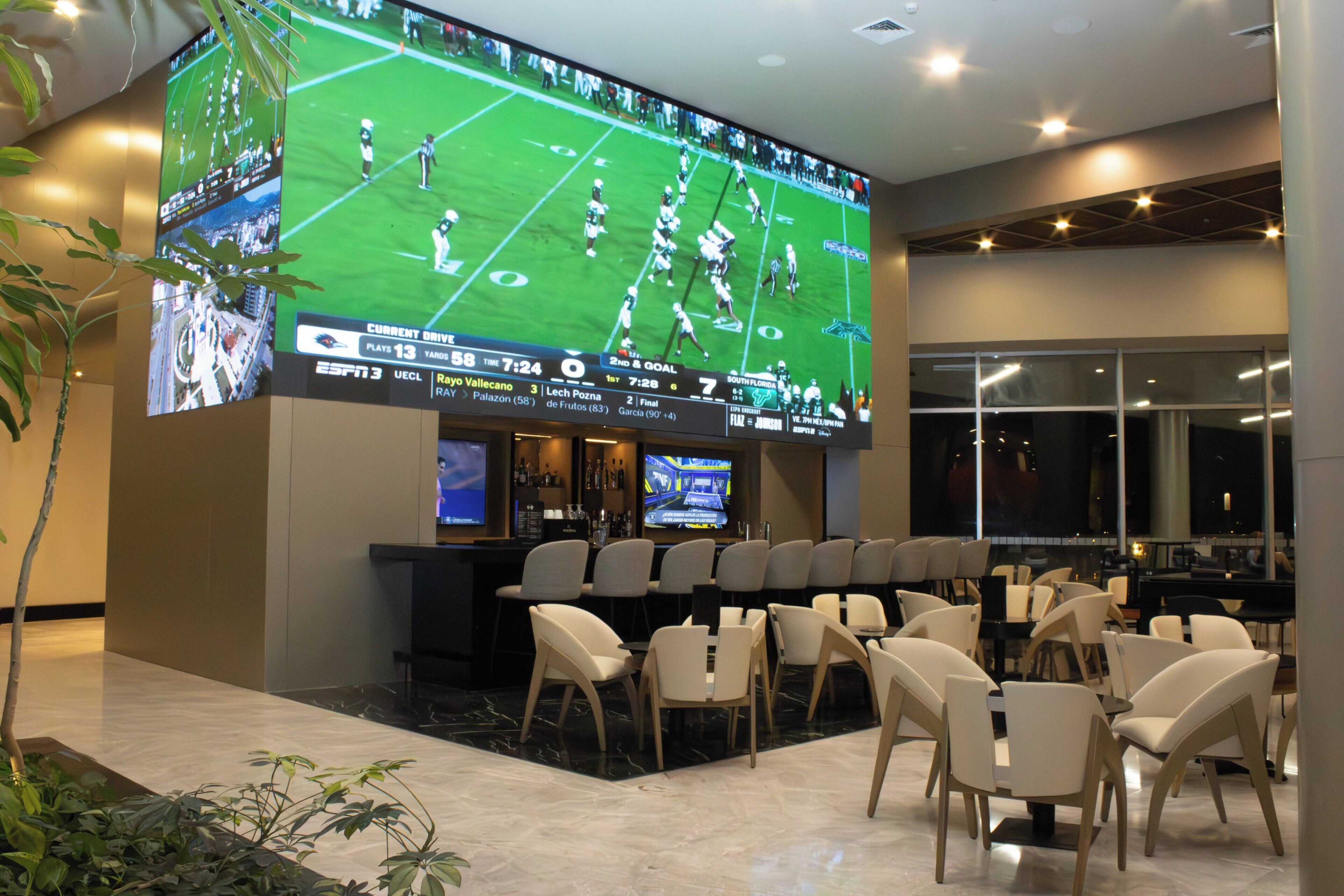 Un bar esportiu amb diverses televisions, zona de bar i seients.