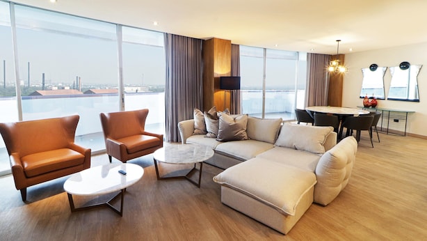 Een moderne woonkamer met een bank, fauteuils, een salontafel en een eettafel.
