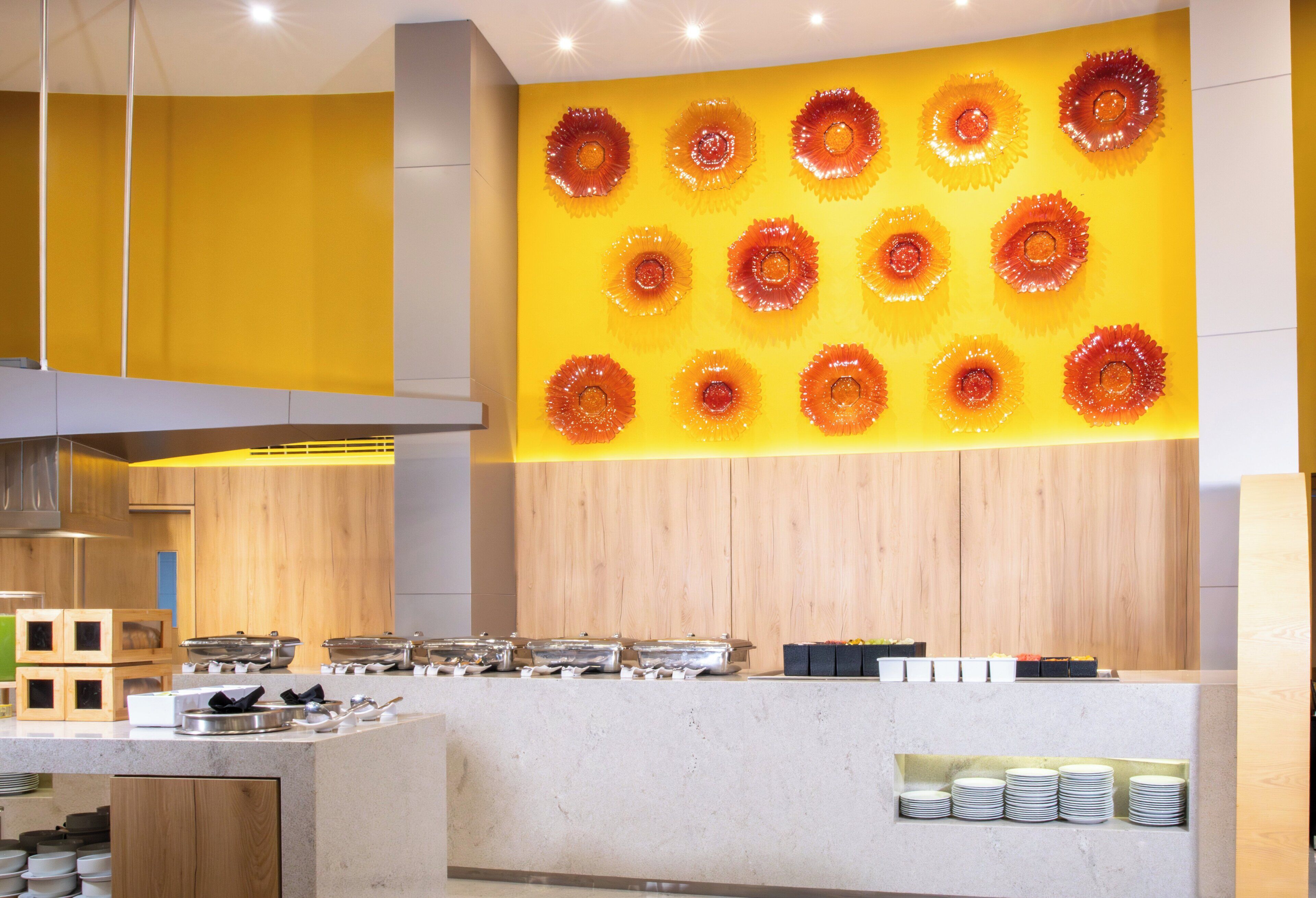 Una cocina moderna con una pared amarilla y una original pieza de arte en vidrio.