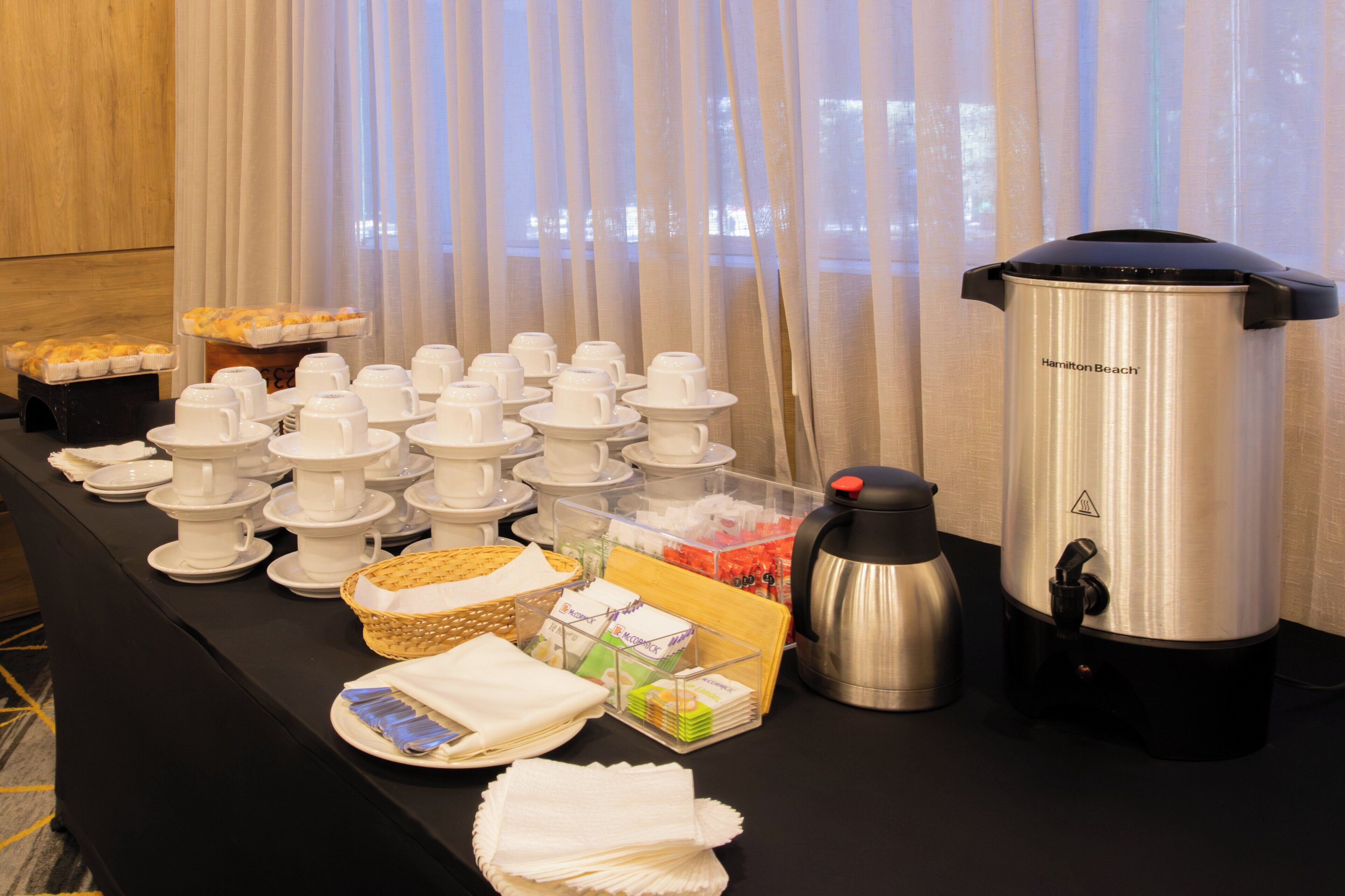 Un buffet con tazze bianche, una macchina per il caffè e un cestino di pane.