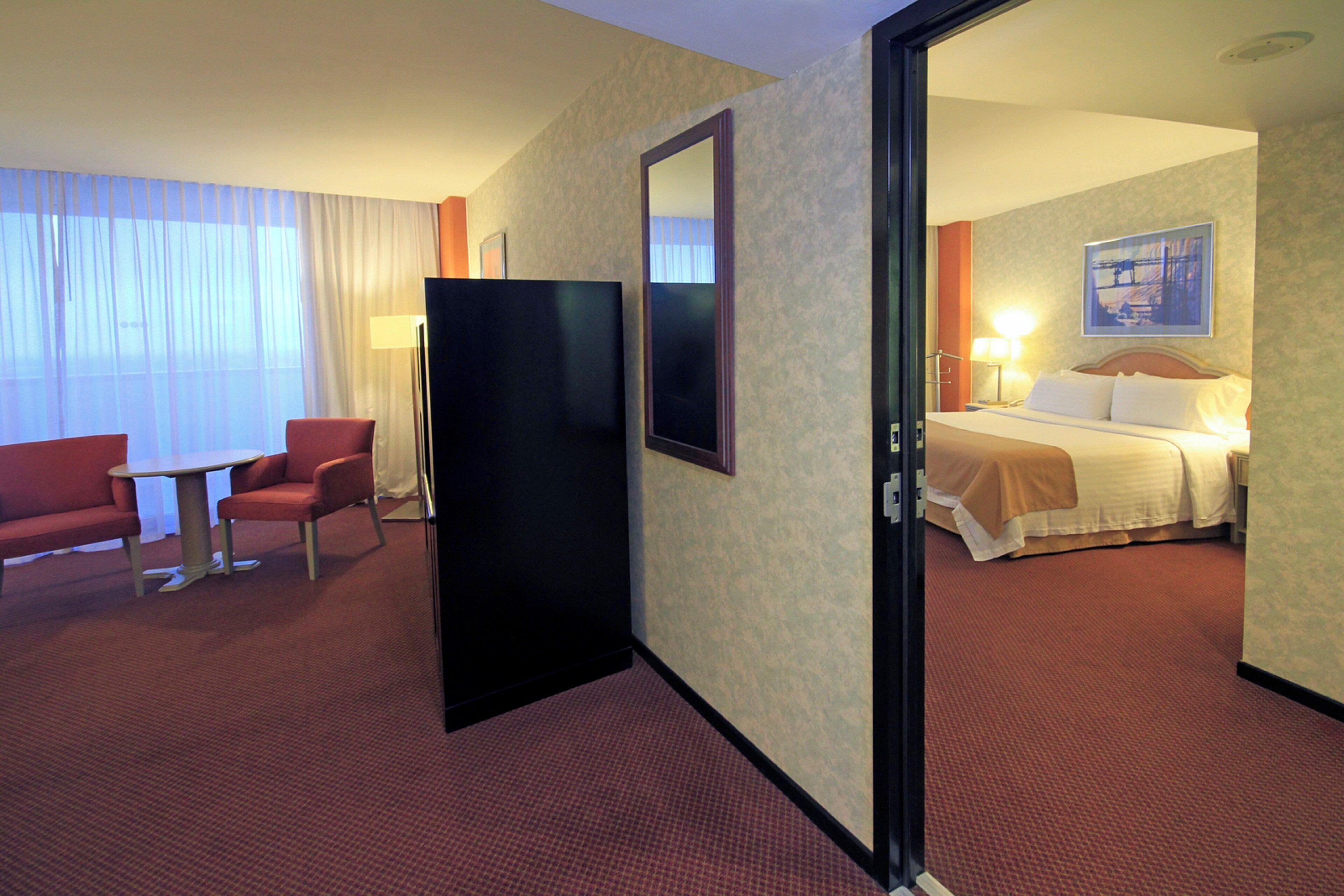 A hotel room with a bed, a desk, a chair, and a large mirror.