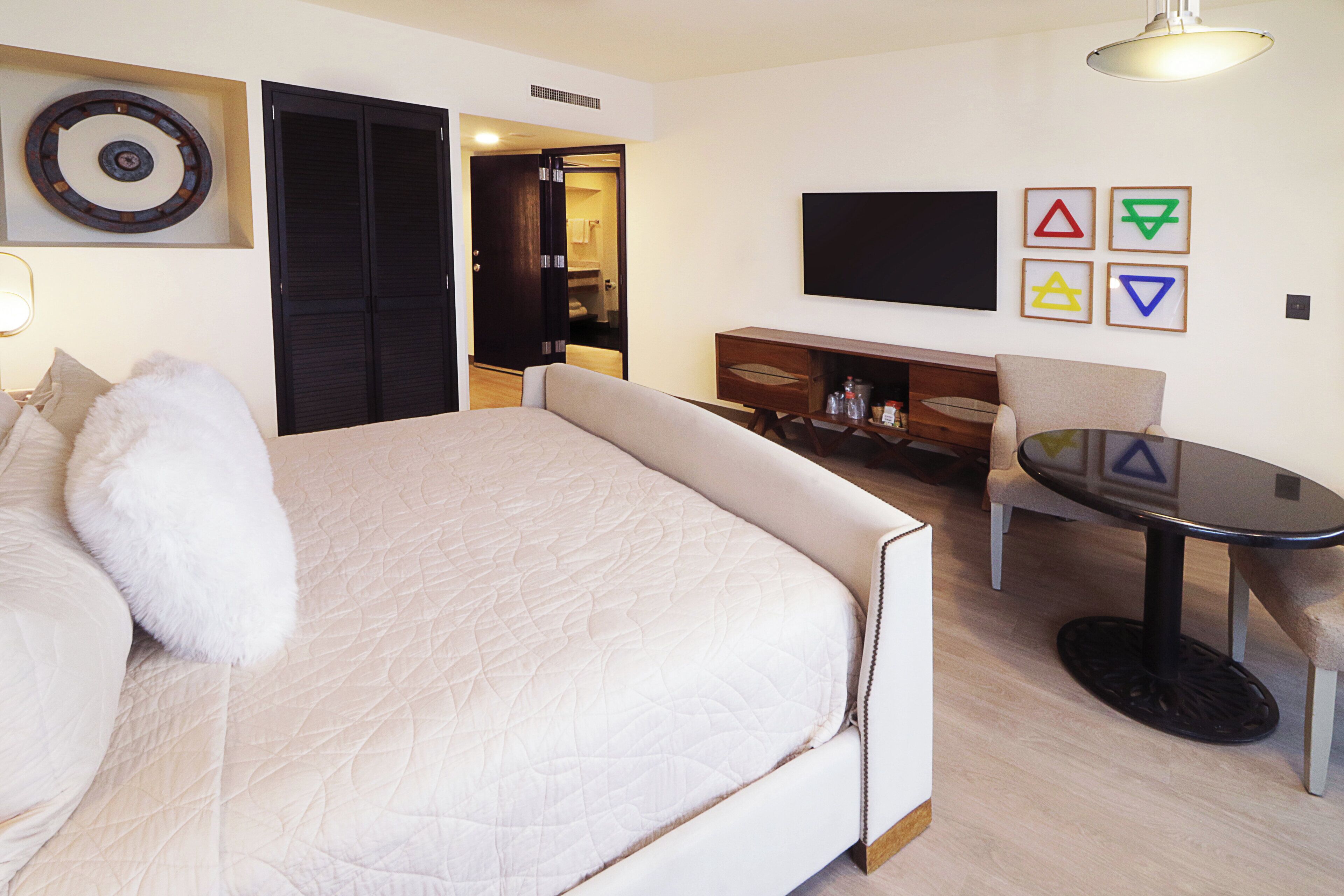 A hotel room with a bed, a small table, a TV, and a wardrobe.