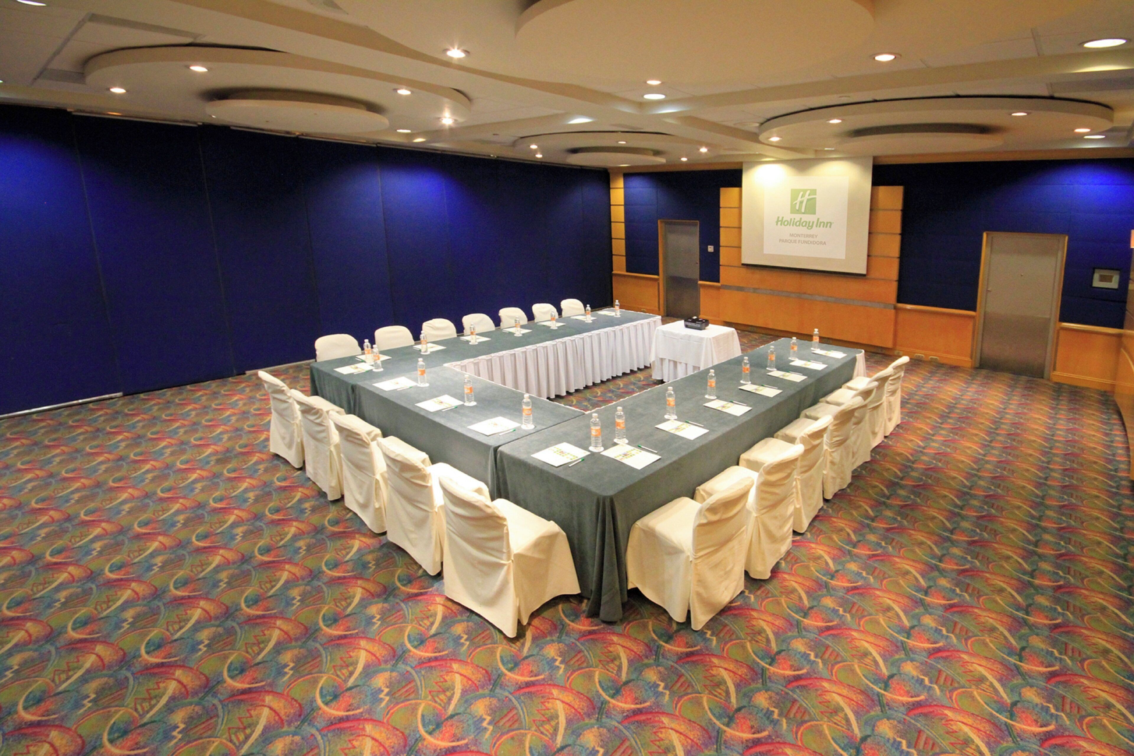A conference room with a long table, chairs, and a podium.