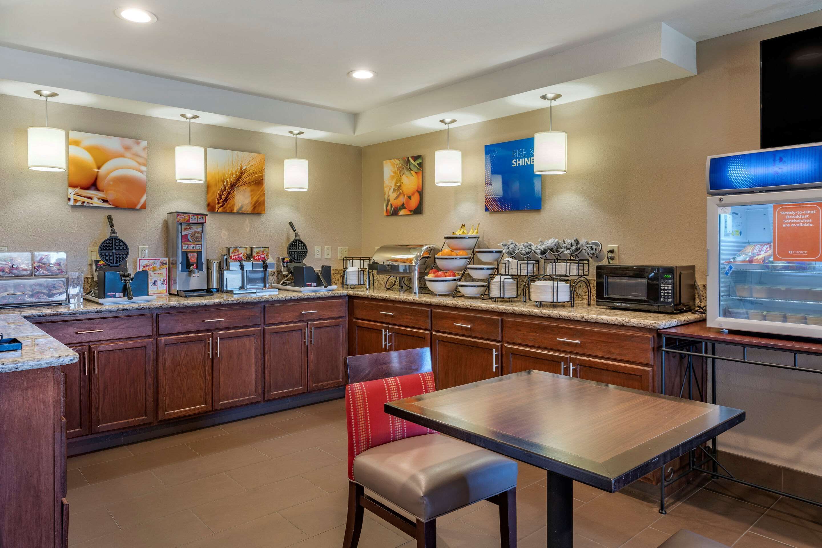 A hotel breakfast area with a buffet setup, including a microwave, toaster, and various food items.