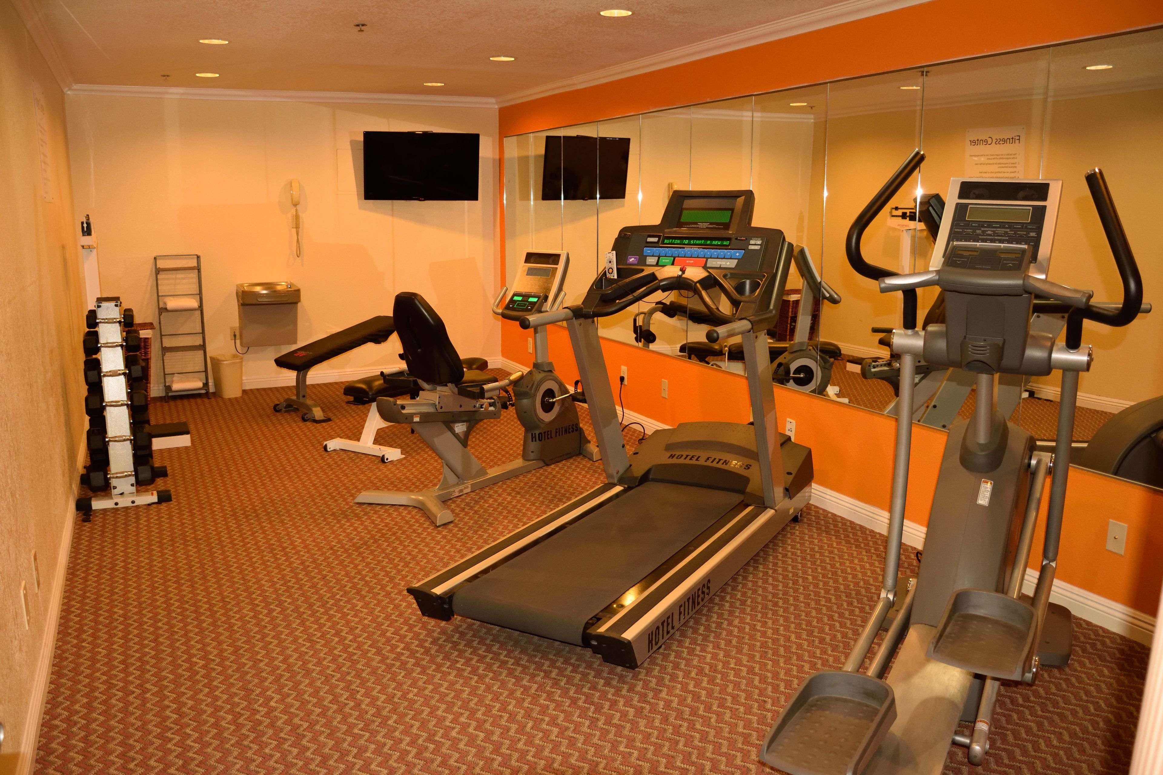 A hotel fitness center with treadmills, elliptical machines, and free weights.