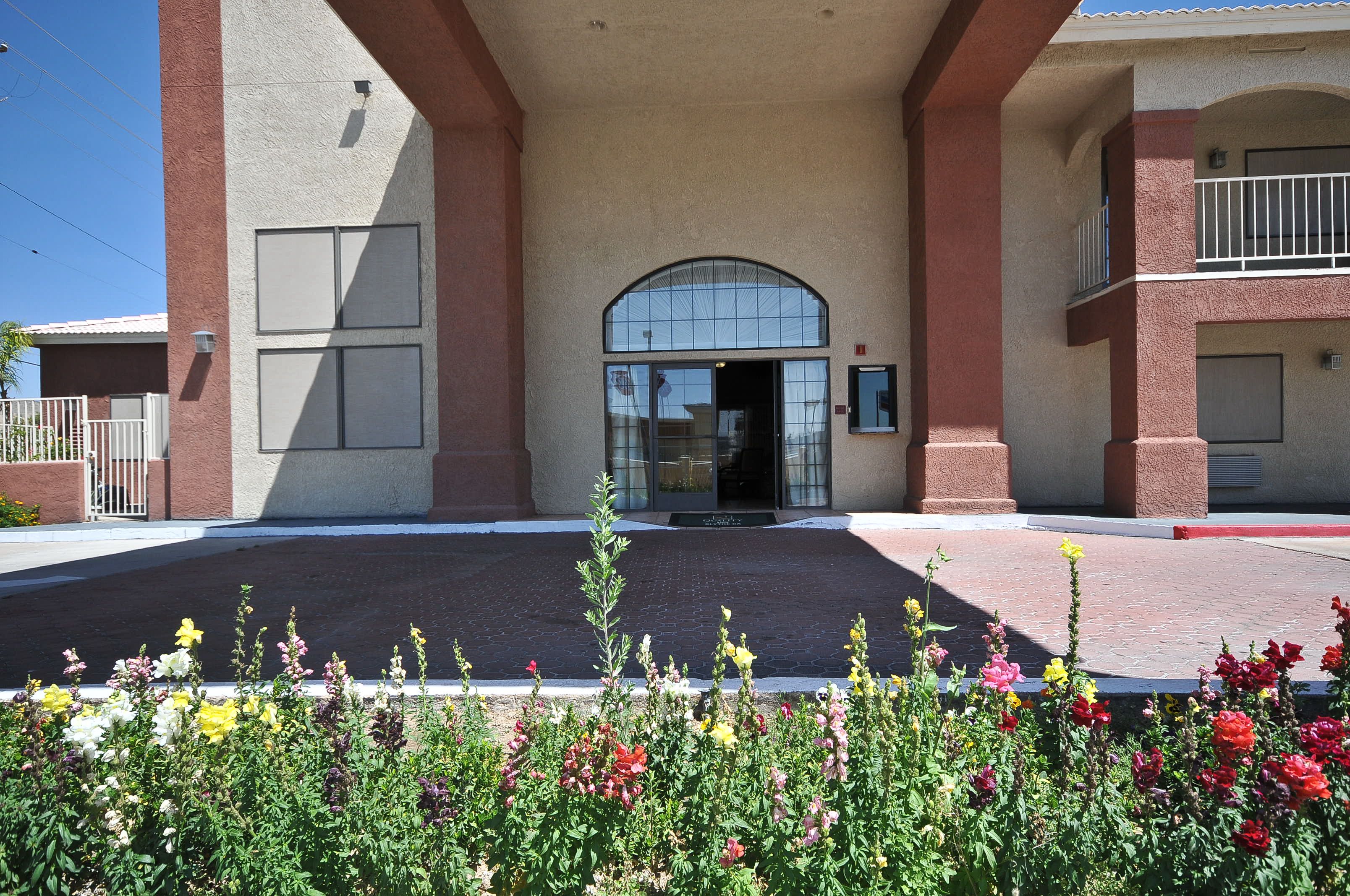 A building entrance with a glass door, a red brick facade, and a small balcony.