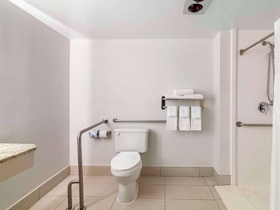 Un bagno moderno dotato di toilette, maniglie di sostegno, portasci e zona doccia.