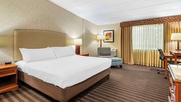 A hotel room with a large bed, a desk, a chair, a lamp, and a television.