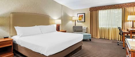 Une chambre d’hôtel avec un grand lit, un bureau, une chaise, une lampe et un téléviseur.