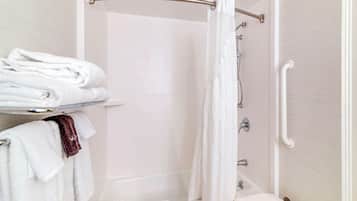Un baño con ducha, inodoro y lavabo. Hay toallas en un estante y una cortina de ducha.