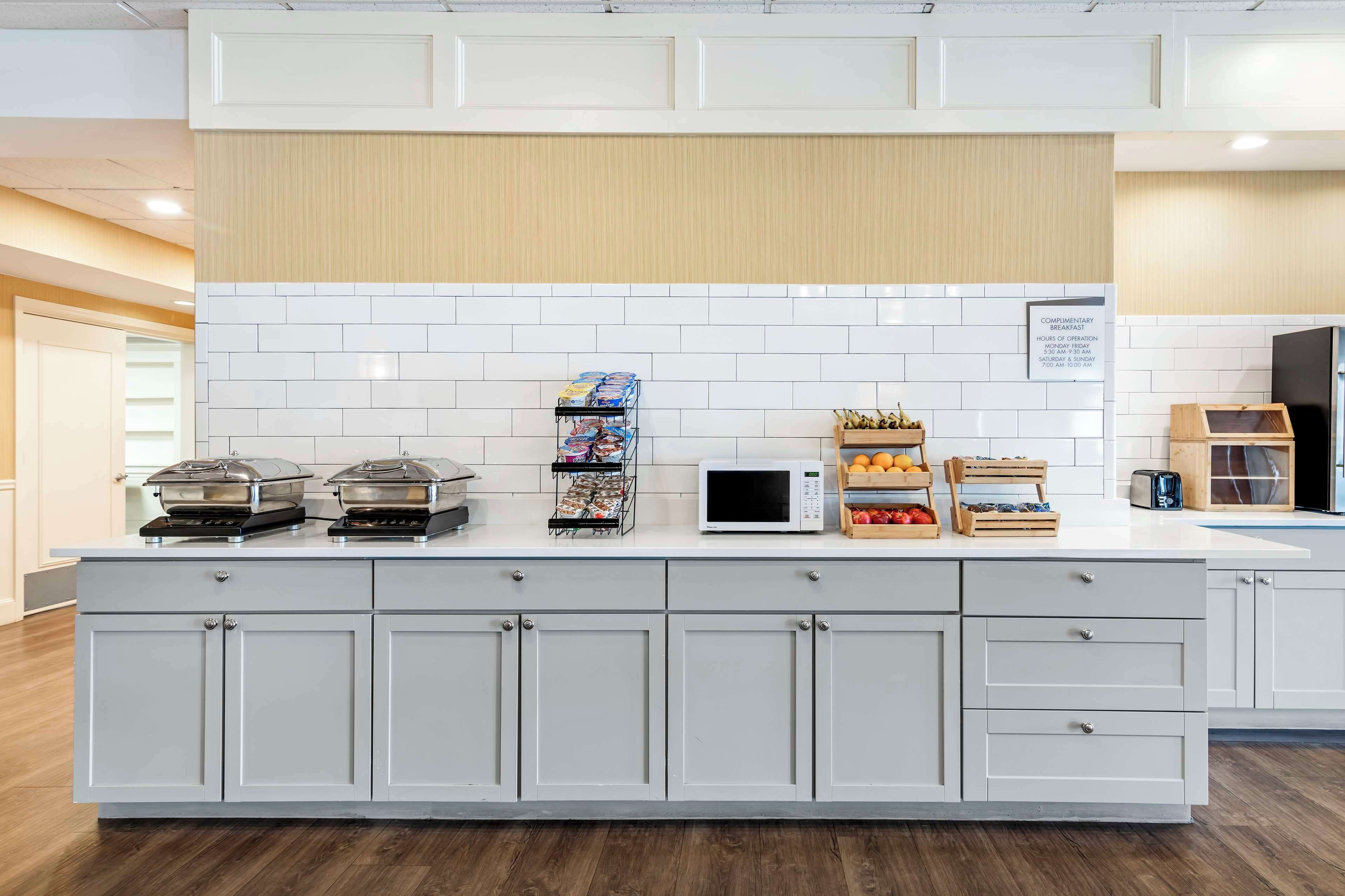 A modern kitchen with a white tiled backsplash, a built-in microwave, and a variety of food items on the counter.