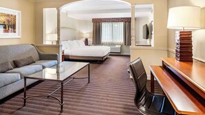 A hotel room with a bed, a sofa, a coffee table, a desk, and a TV. - Best Western Springfield Hotel (Springfield)
