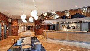 Un moderno vestíbulo de hotel con mostrador de recepción, zona de estar y mostrador de salida.