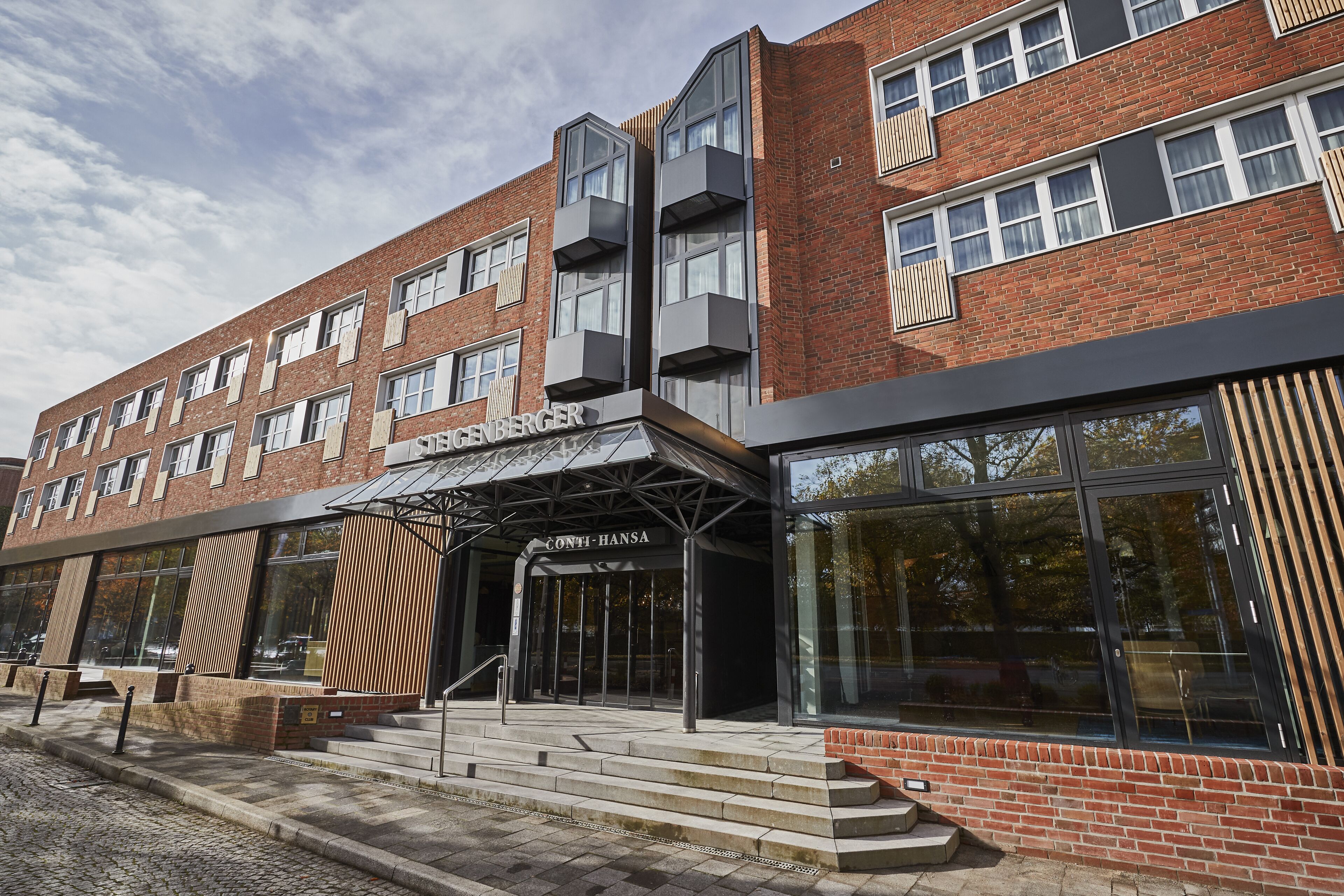 A modern building with a brick facade, large windows, and a prominent entrance with a canopy.