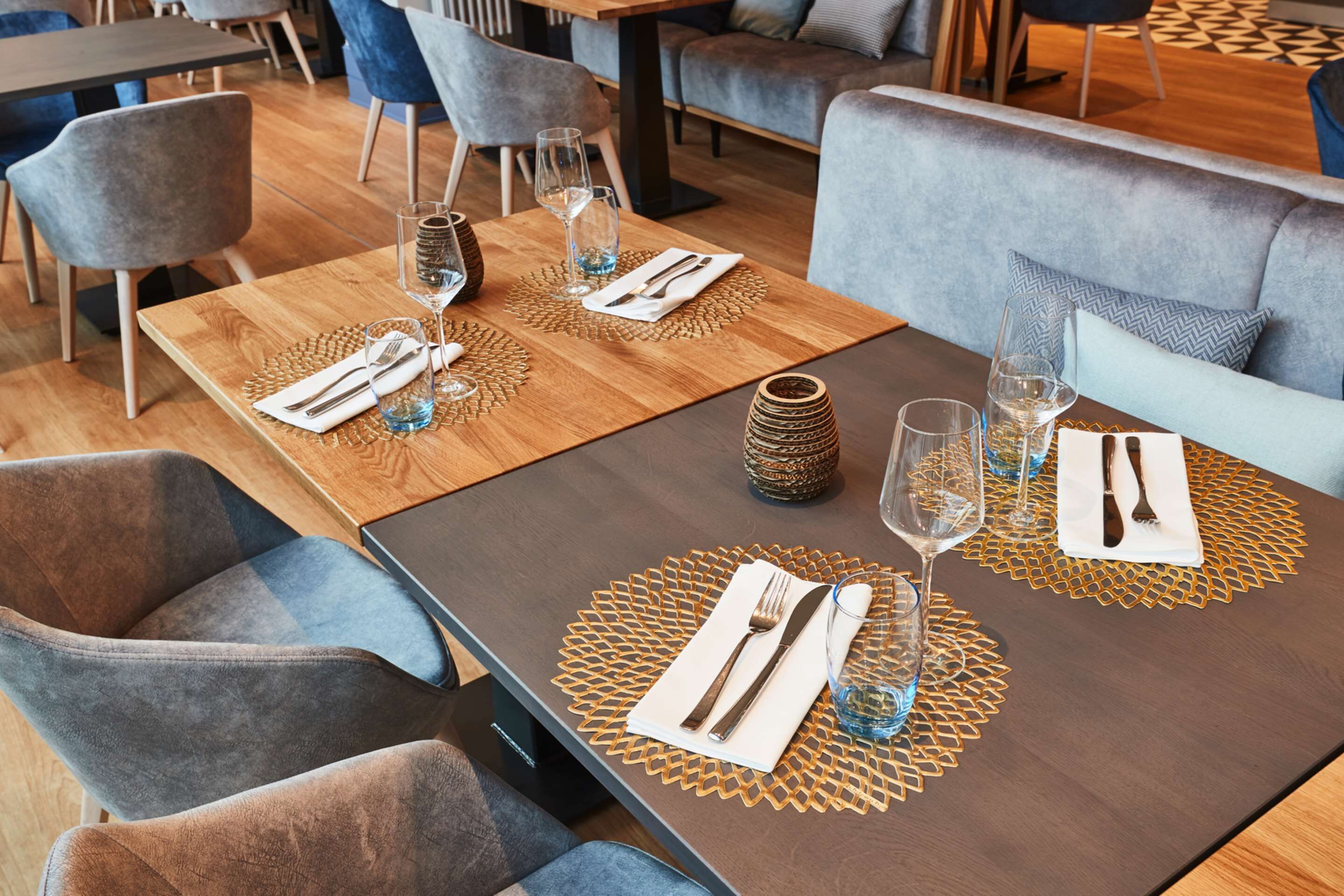 A restaurant with tables set with white napkins, cutlery, and wine glasses.