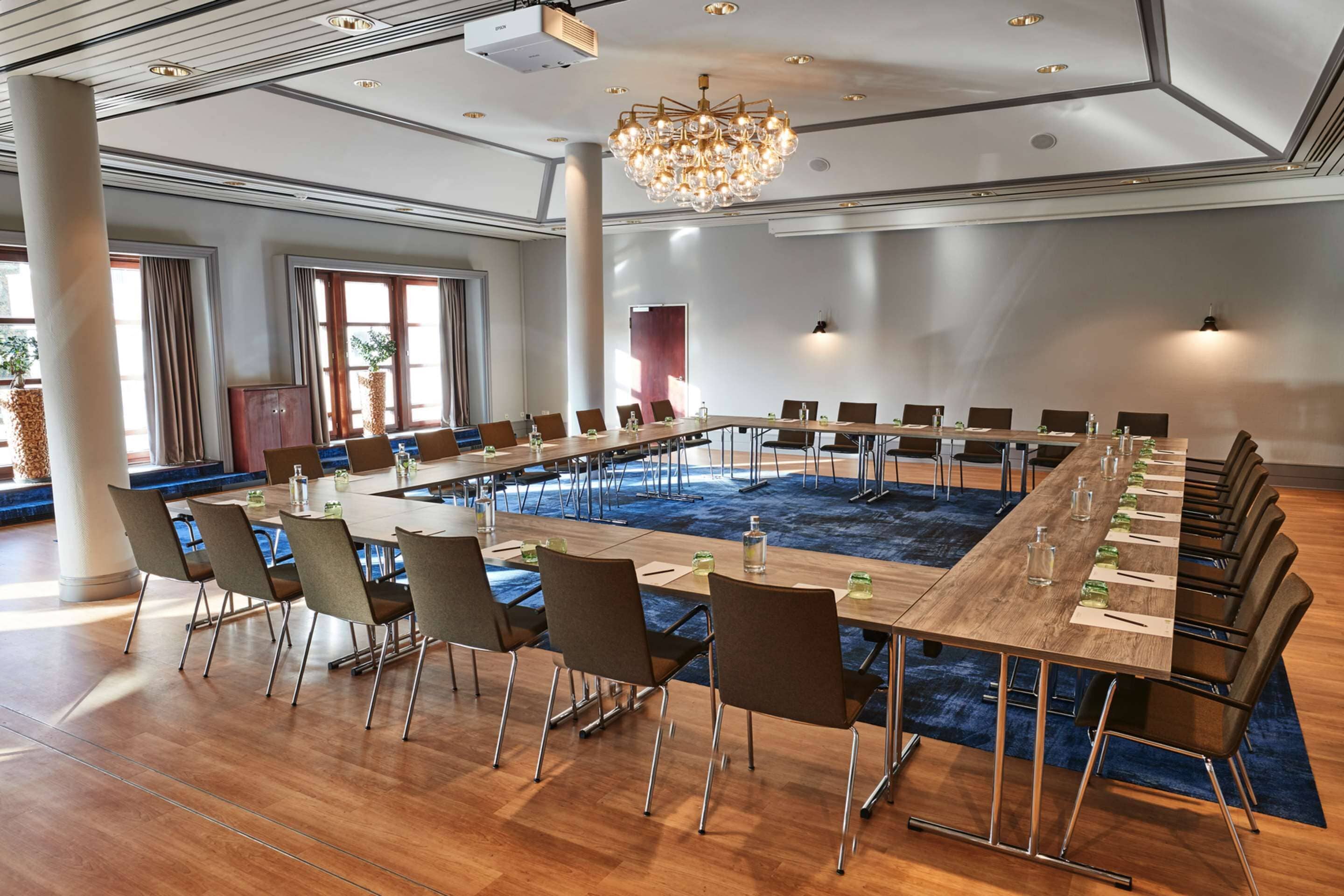Ein großer Konferenzraum mit einem langen Tisch, mehreren Stühlen und einer Kristallleuchter.