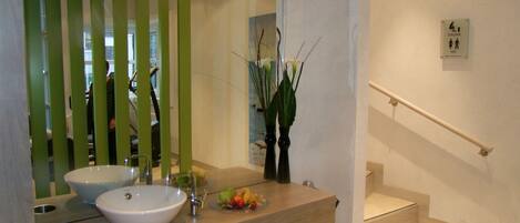 A modern bathroom with a large mirror, a sink, and a small staircase.