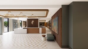 A modern hotel lobby with a reception desk, pendant lighting, a herringbone patterned floor, and a large painting on the wall. - Holiday Inn Cleveland Airport West by IHG (North Olmsted)