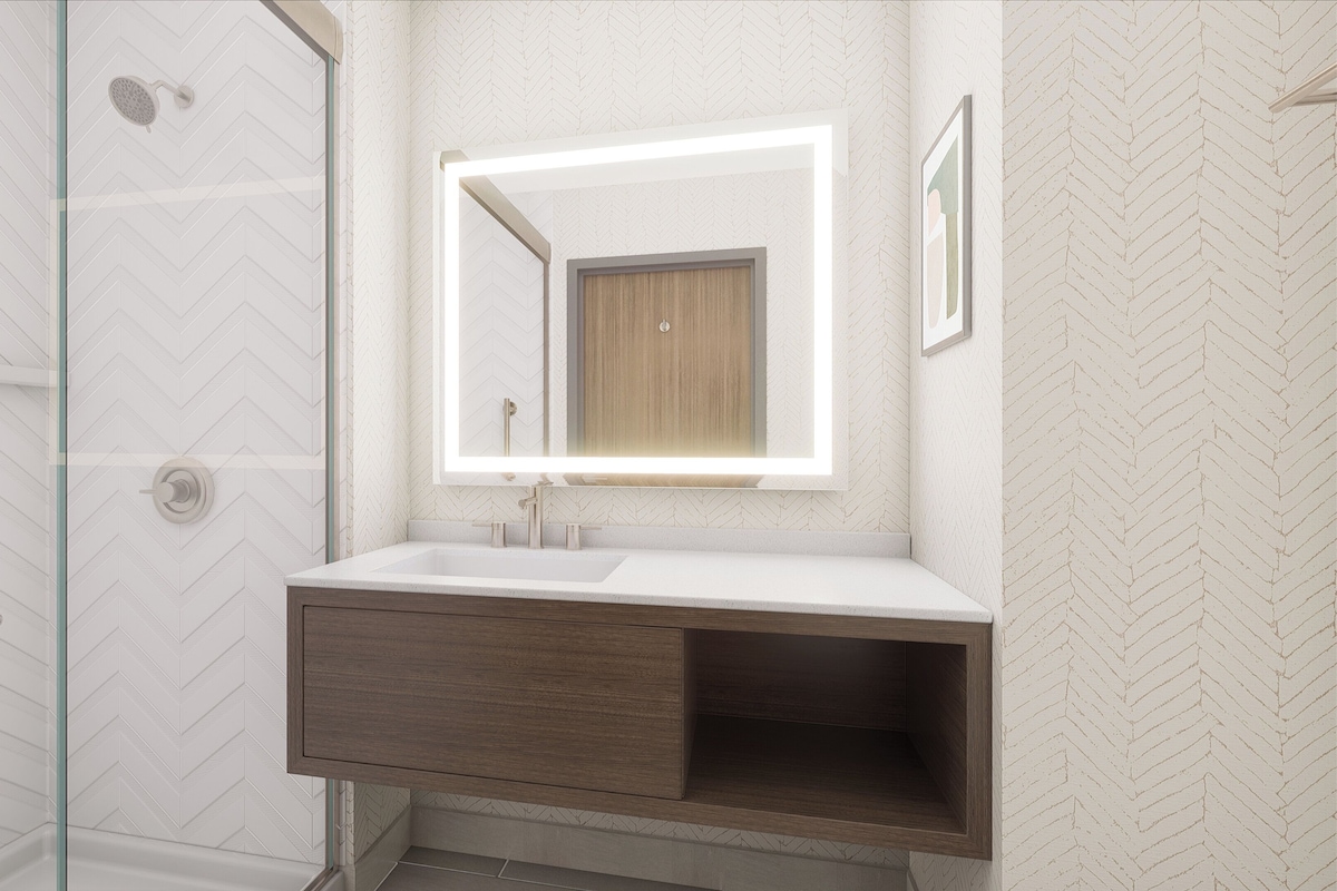 A bathroom with a shower, a vanity with a mirror, and a herringbone-patterned wall.