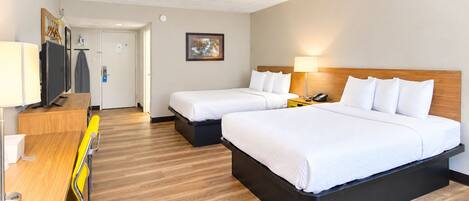A hotel room with two beds, a desk with a chair, a television, and a painting on the wall.
