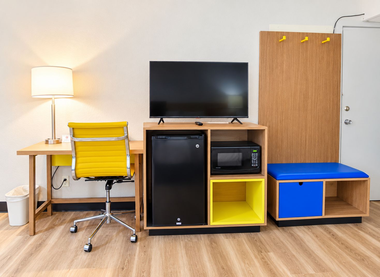 Een knus ingerichte kamer met een bureau, stoel, televisie, minibar, magnetron en een kledingkast.