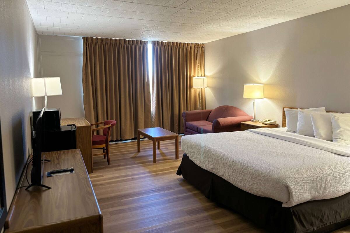 A hotel room with a bed, desk, chair, and two lamps.