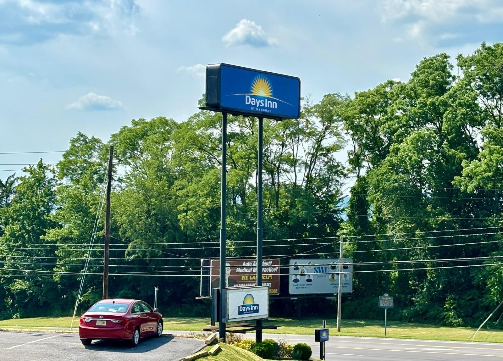 Señal de Days Inn con fondo azul y un logo de sol.