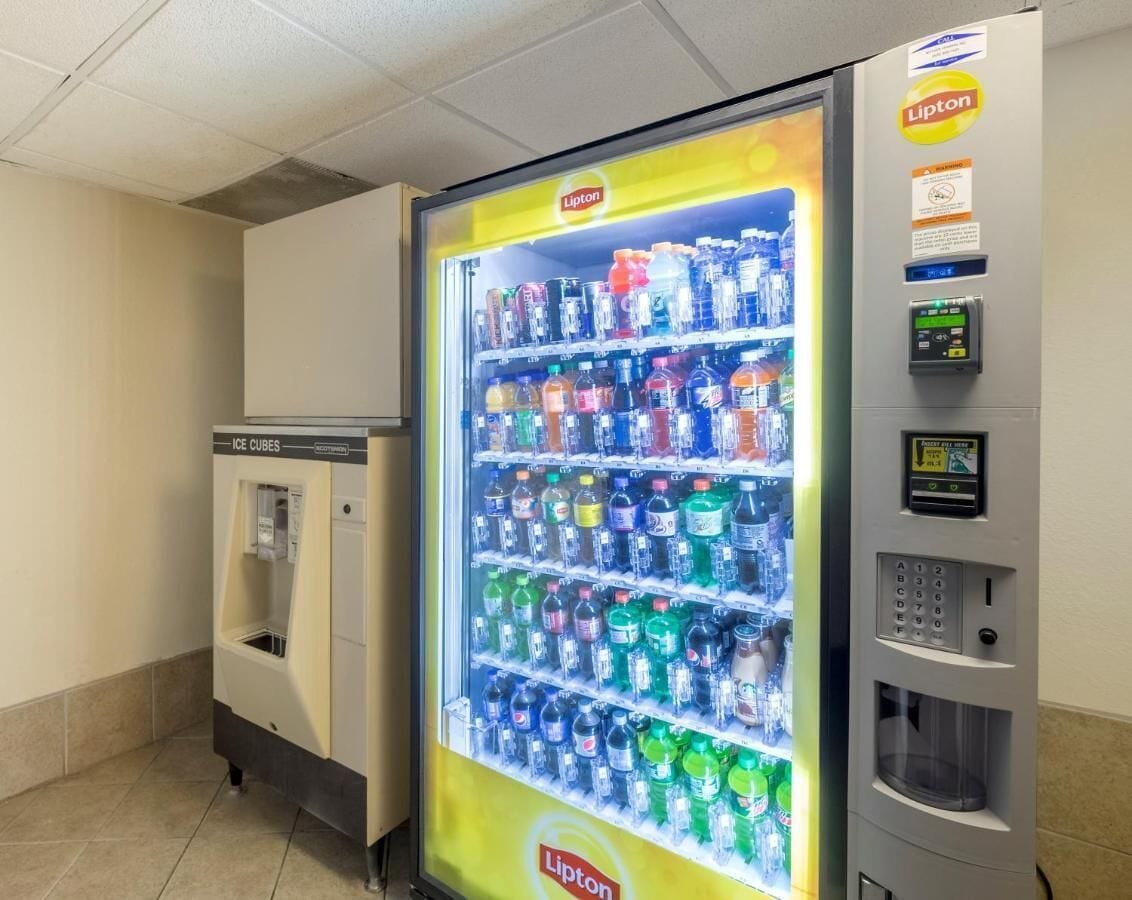 Un distributeur automatique rempli de diverses boissons, un distributeur de glaçons séparé et un terminal de paiement.