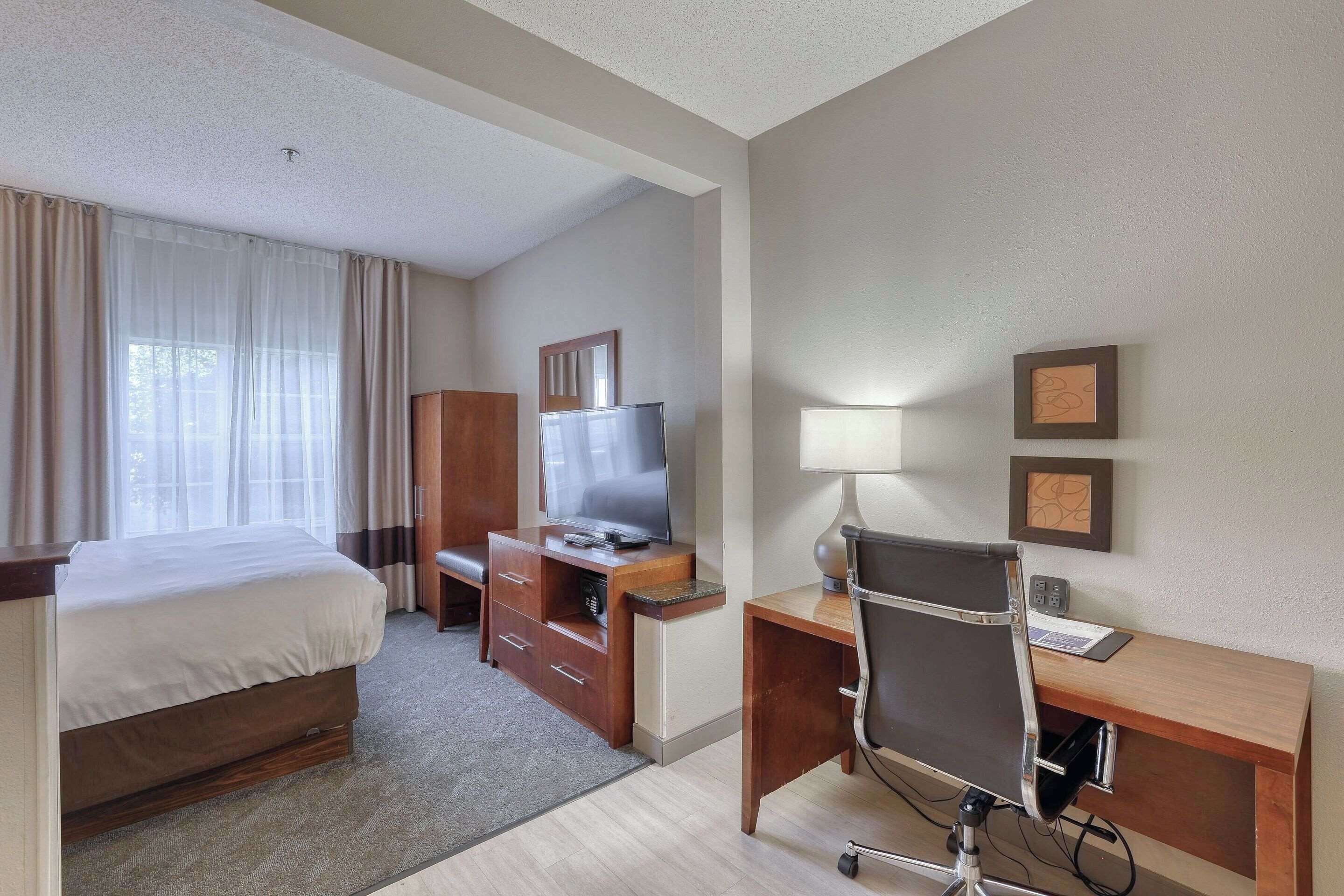Une chambre d’hôtel comprenant un lit, un bureau avec une chaise, une télévision et une lampe de bureau.
