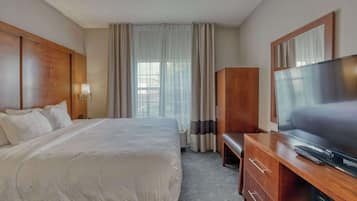 Una habitación de hotel con una cama grande, un escritorio de madera con televisor y un armario.