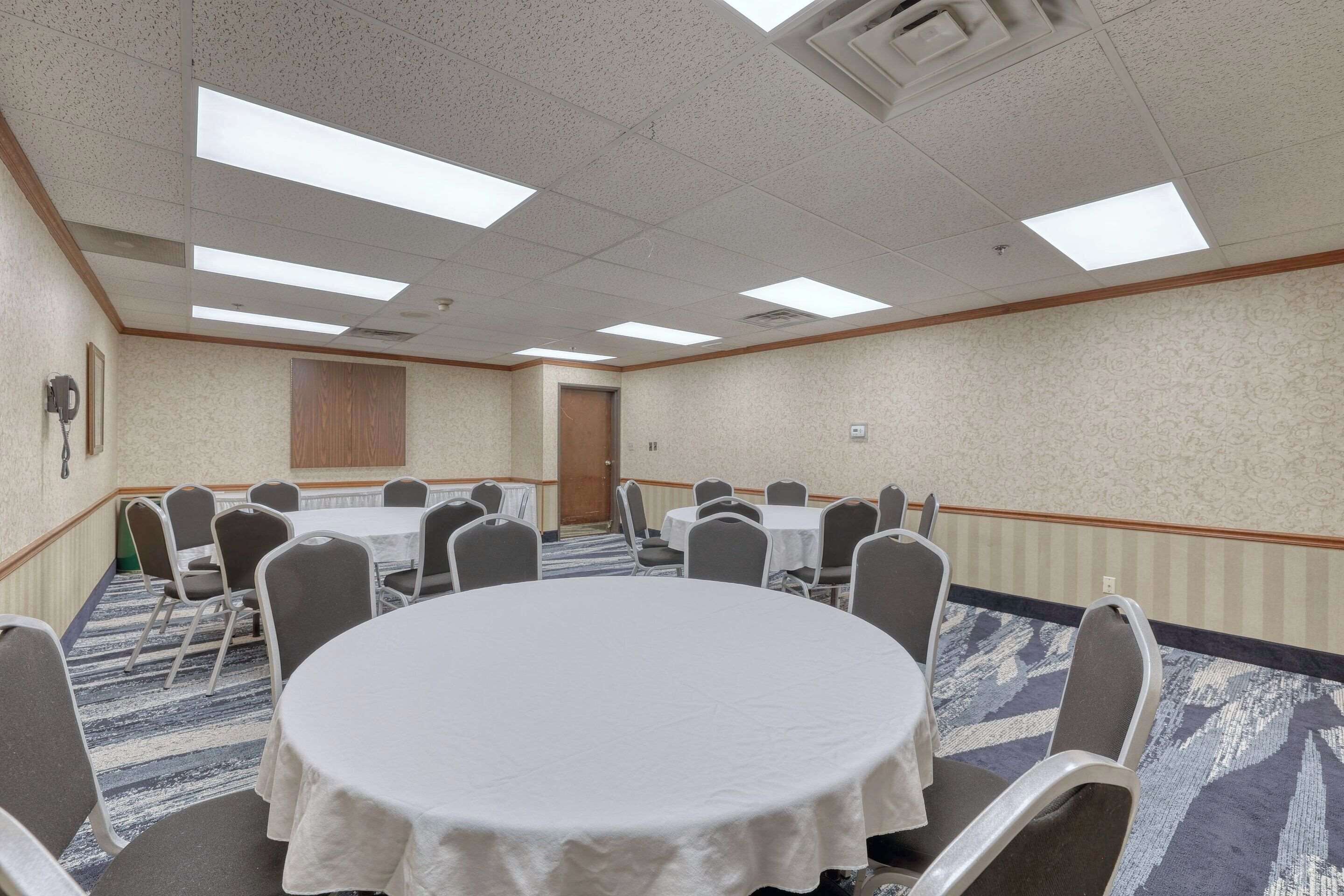 A conference room with a round table, rectangular tables, and chairs.
