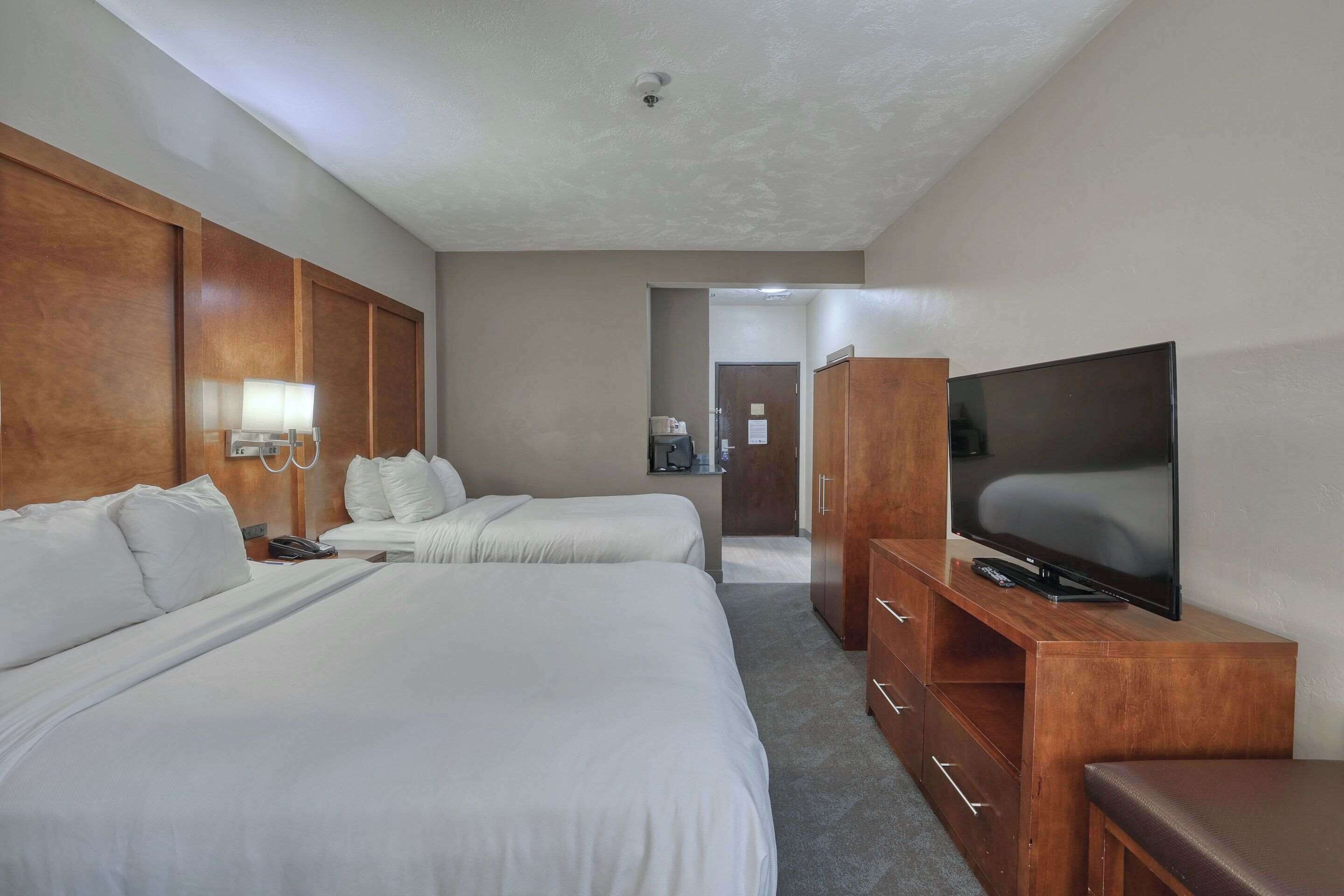 A hotel room with two beds, a TV, a desk, and a wardrobe.