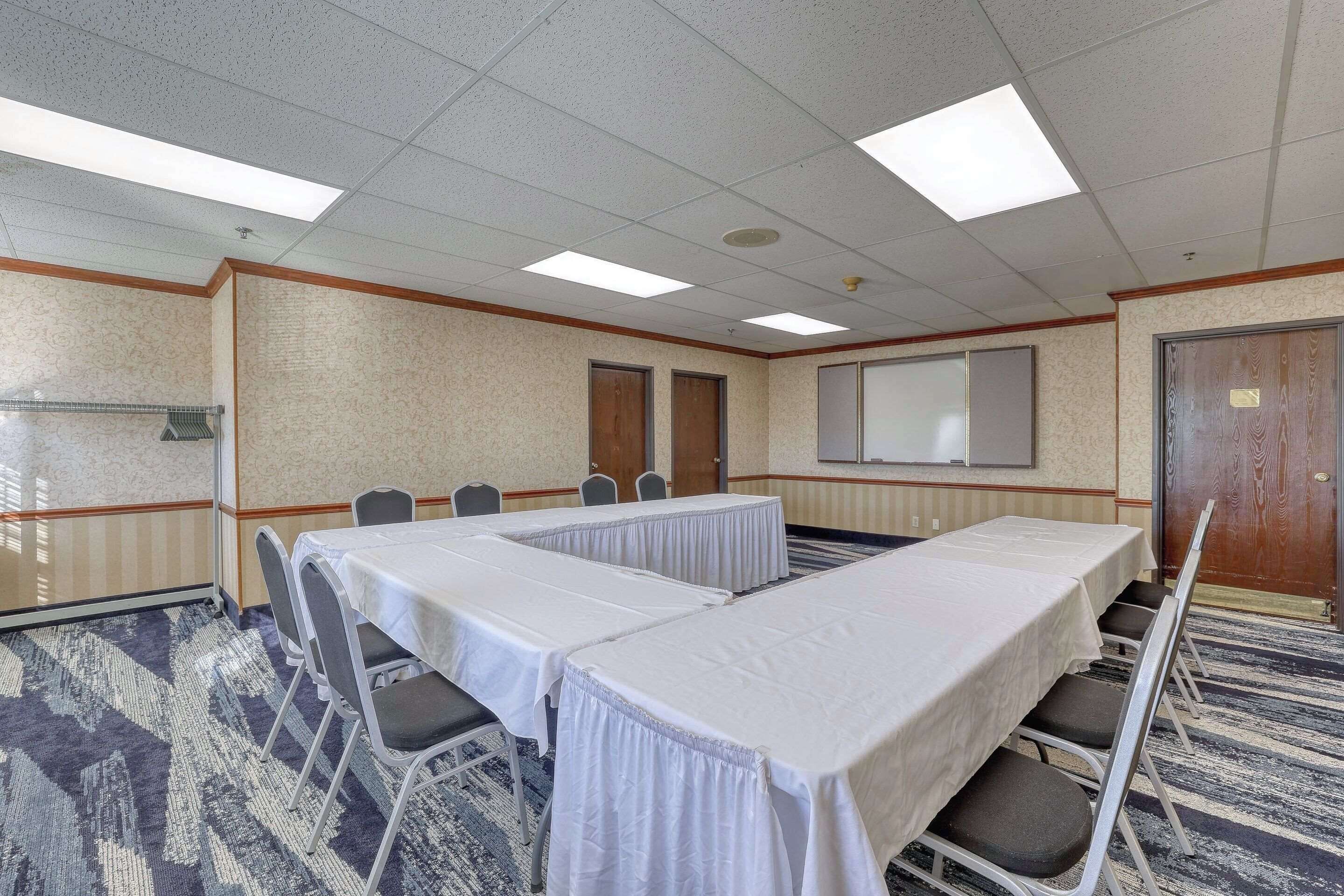 A conference room with a long table, chairs, a projector screen, and a door.
