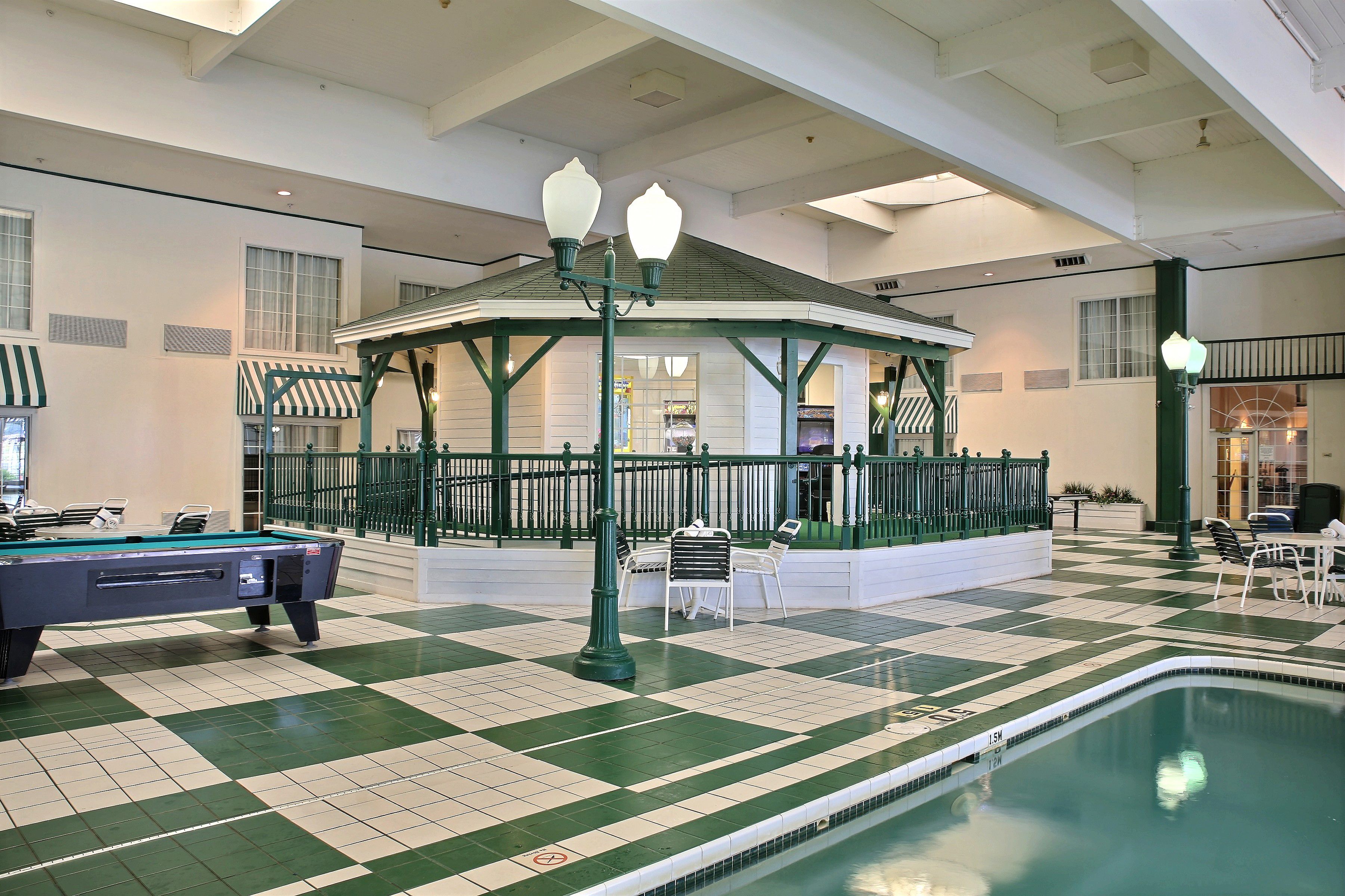 A pool area with a checkered floor, a pool table, and a gazebo.