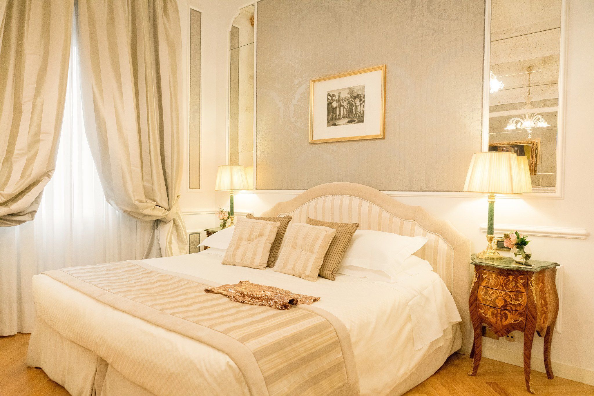 A neatly made bed with a striped blanket, a bedside table with a lamp, and a framed picture on the wall.