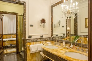 A luxurious bathroom with two sinks, a large mirror, and a chandelier.