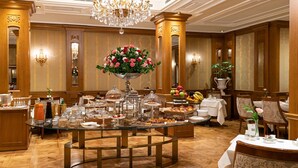Montaje tipo bufé con diversas opciones de comida, un arreglo floral central y una decoración elegante que incluye candelabros y paneles de madera.