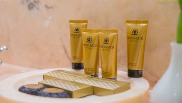 Une salle de bain avec un lavabo en marbre, trois flacons d’après-shampoing Trussardi My Land et un porte-savon contenant un pain de savon.