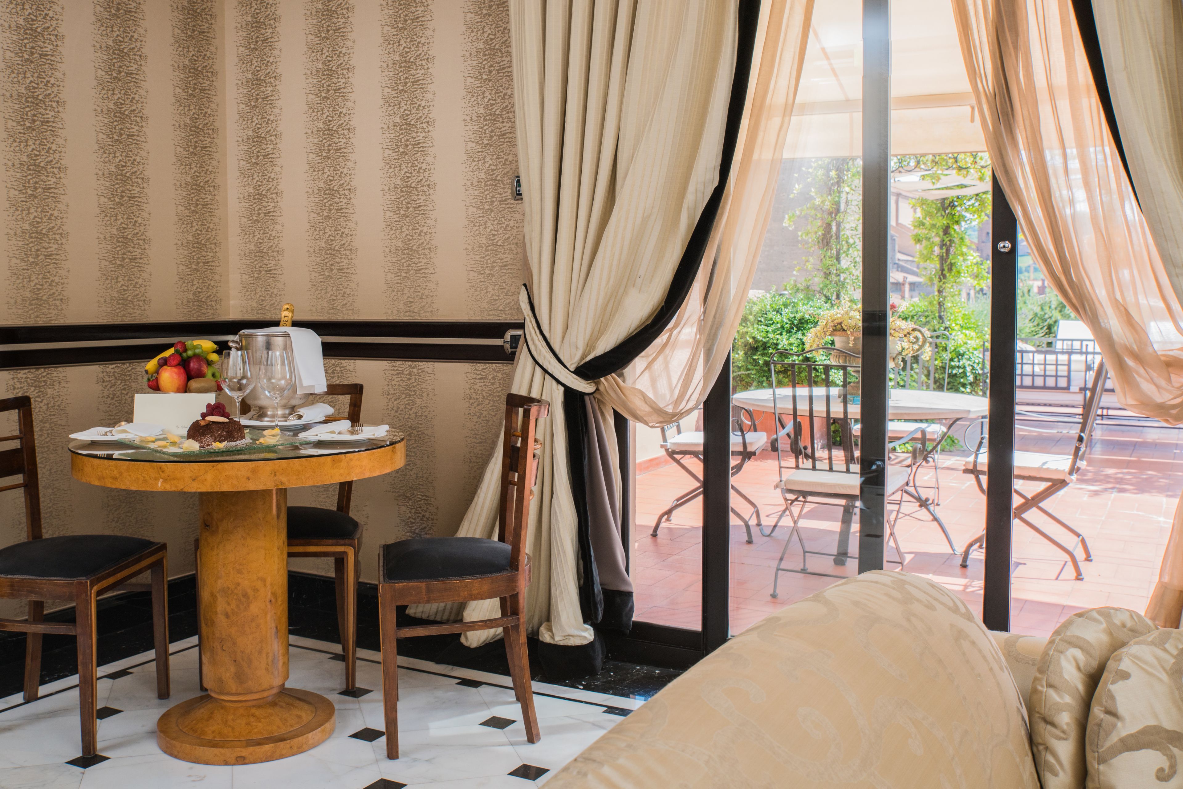 Een kamer met een eettafel gedekt voor twee personen, een bank en uitzicht op een terras.