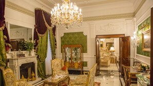 Una habitación lujosa con muebles ornamentados, un candelabro y una chimenea.