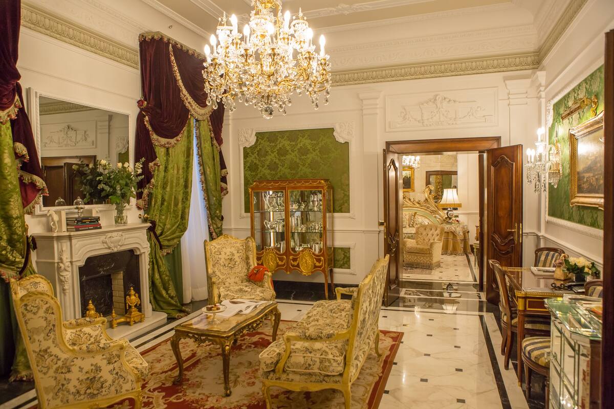 Una habitació luxosa amb mobles ornamentals, un candelabrum i una llar de foc.