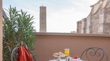 Una mesa dispuesta con cosas para el desayuno, un vaso de zumo de naranja y vistas a edificios históricos.
