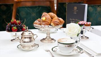 Een tafel gedekt met gebak, een theepot, een kop koffie en een menukaart.