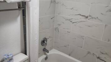 A bathroom with a bathtub, toilet, and a shower curtain.